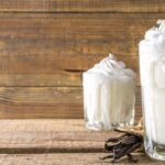 Vanilla milkshakes with whipped cream on wood table